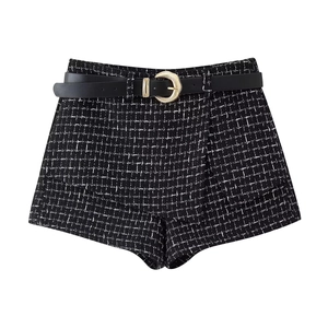 Dettaglio degli shorts a trapezio in tweed con cintura in pelle nera e fibbia d'oro