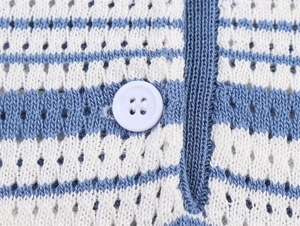 Détail de maille rayée bleue et blanche avec texture pointelle et un bouton blanc