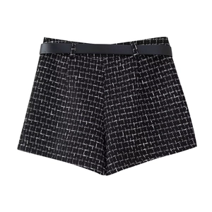Dettaglio di pantaloncini in tweed bianco e nero a vita alta con cintura in pelle