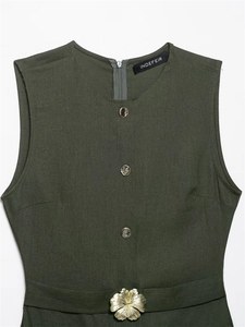 Detail of dark green sleeveless dress with golden floral buckle and silver buttons