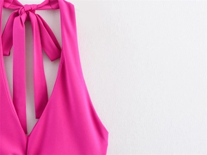 Detail of fuchsia halter dress featuring deep V-neck and a large decorative neck bow tie
