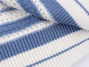 Détail du tricot rayé bleu et blanc avec motifs ajourés et bord-côte au bas du vêtement