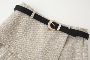 Dettaglio della trama in tweed con cintura nera e fibbia dorata sui pantaloncini