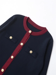Gros plan sur le col rond, boutons dorés et bordures bordeaux du cardigan en tricot bleu marine