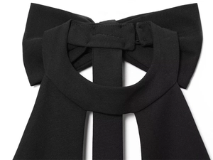 Dettaglio di un abito nero all'americana con un grande fiocco sul retro e ritagli