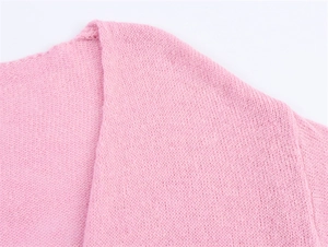 Nahaufnahme des rosa Strickstoffs mit feiner Textur und weichen Details der Strickjacke