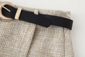 Dettaglio degli shorts in tweed beige con cintura in pelle nera e fibbia dorata