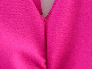 Macro shot of rose pink tight knit fabric showing V-neckline and neat stitching detail