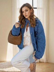 Détail de la veste matelassée bleue avec surpiqûres et sac tressé marron vintage