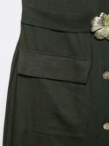 Detailed macro view of dark green linen fabric with golden floral accent and metal buttons