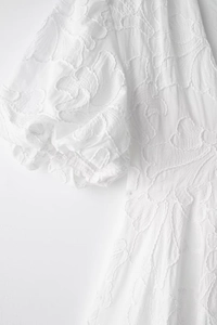 Detail of 3D floral embroidery and puffed sleeves on white V-neck mini dress