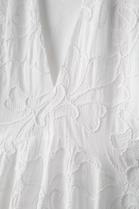 Detailed macro view of white embroidery and deep V-neckline on cotton dress fabric