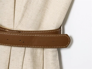 Detail of a brown leather belt with contrast stitching on beige twill fabric texture
