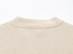 Detail of a beige knitted round neckline with double stitching and textured fabric