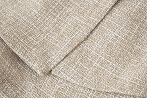Dettaglio del tessuto in tweed beige con filo metallico dorato e trama intrecciata spessa