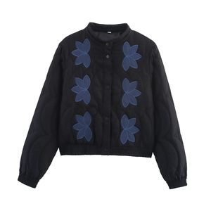 Détail d'une veste matelassée noire avec broderies florales bleues et pressions