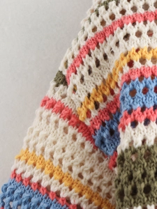 Detailed close-up of colorful striped crochet polo knitwear with hollow-out texture