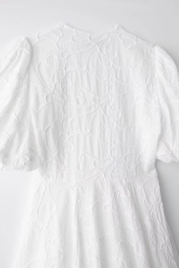 Detail of white puff sleeve dress featuring intricate 3D floral embroidery and texture