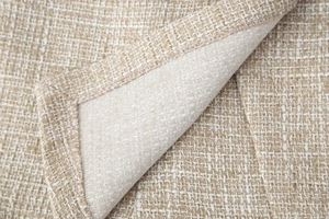Dettaglio del tessuto tweed beige con fili dorati metallizzati e cuciture sui bordi