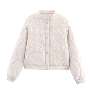 Détail du matelassage floral brodé et fermeture à boutons sur la veste d'hiver crème
