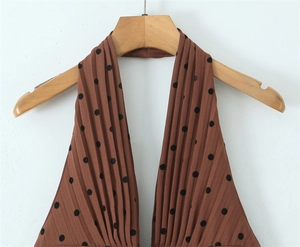 Détail du tissu plissé marron à pois sur une robe à col licou avec décolleté en V