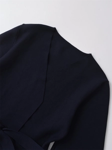 Detail of the deep blue wrap V-neck knit top showing the waist tie and fabric texture