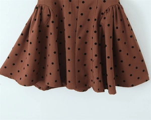Détail du tissu marron à pois noirs avec un ourlet à volants plissés élégant