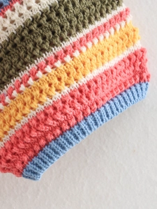 Detail of colorful striped crochet polo set showing textured knit and ribbed cuffs
