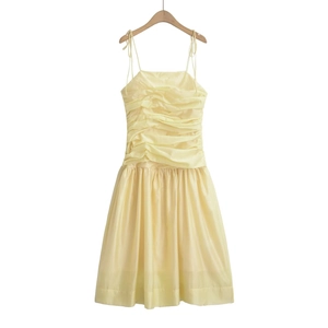 Detail of light yellow midi dress featuring delicate pleats and thin spaghetti straps