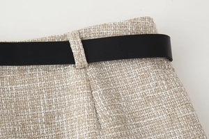Dettaglio della trama in tweed e della cintura in pelle nera sugli shorts a vita alta