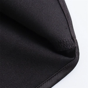 Macro shot of precise edge stitching and twill texture on a black satin dress