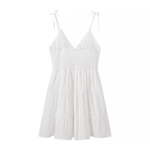 Detail of white embroidered v-neck dress featuring smocked waist and tiered skirt layers