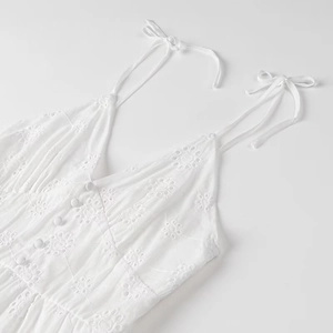 Detail of white summer dress showing floral eyelet embroidery and adjustable tie straps