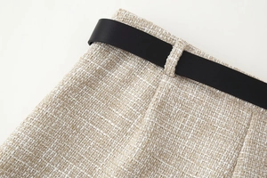 Vista dettagliata della trama in tweed beige con una cintura minimalista in pelle nera