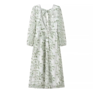 Détail de la robe longue blanche avec broderie florale verte et dentelle à la taille