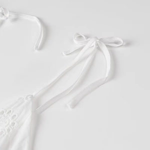 Detailed view of white eyelet embroidery and adjustable tie shoulder straps on summer dress