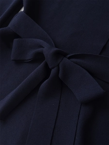 Detail of navy blue ribbed knit dress showing a neatly tied waist bow and premium texture