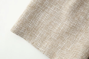 Dettaglio del tessuto in tweed beige con motivi a trama di alta qualità e consistenza unica
