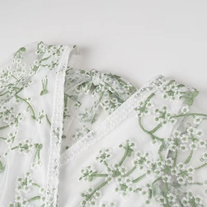 Détail de la robe en tulle blanc avec broderie florale verte et nœud au dos