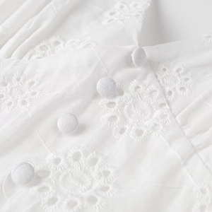 Detail shot of white eyelet embroidery and fabric covered buttons on a cotton dress