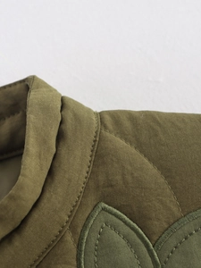 Détail de la veste matelassée vert olive avec surpiqûres et écusson brodé feuille