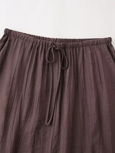 Detail of coffee brown pleated skirt with elastic waistband and drawstring waist