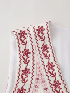 Close-up of red floral embroidery on white cotton vest with intricate wavy stitching