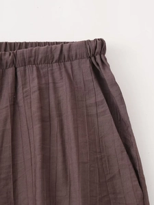 Close-up of brown pleated skirt with elastic waistband and functional side pockets