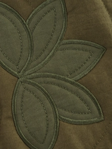 Détail d'une veste en toile vert olive avec broderies appliquées en forme de feuilles