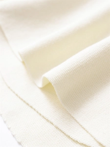 Macro shot of cream knit fabric texture showing premium soft material and ribbed details
