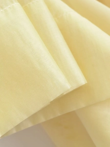 Macro view of light yellow pleated fabric with fine stitching and breathable texture