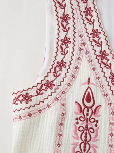 Detail of floral embroidery and vertical pleated fabric on a white bohemian vest
