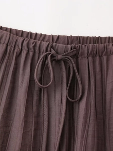 Detail of dark brown pleated skirt waist with elastic band and front drawstring bow