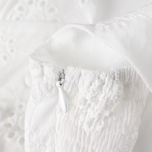 Detail of white summer dress showing hidden zipper and floral embroidery craftsmanship